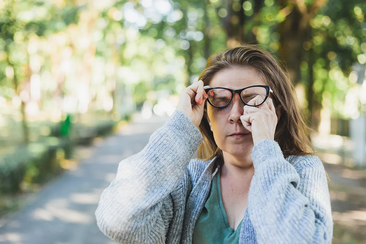 a woman rubbing her eye while walking outside