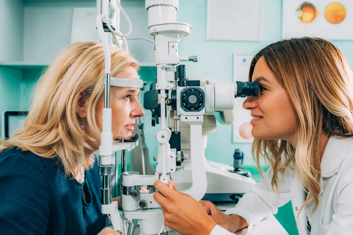 Eye doctor performing a slit-lamp eye exam on a patient in an optometry clinic.